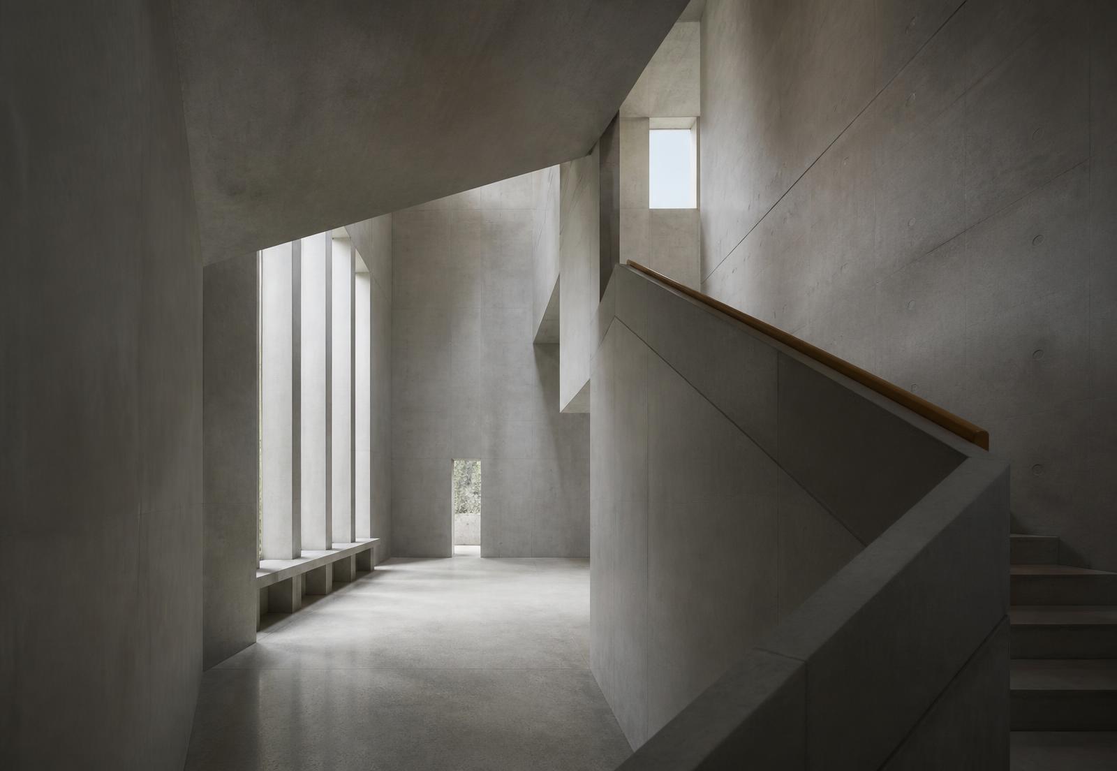Minimal concrete interior with daylight through tall openings